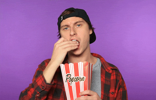 gif of a man eating popcorn and looking intrigued