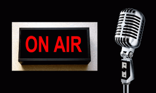 A flashing ON AIR sign with an old fashioned microphone stand in front.