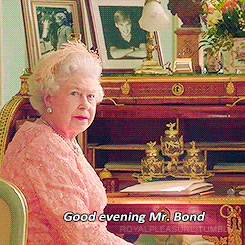The Queen gets up from her seat to greet someone. The caption reads, 'Good evening, Mr. Bond.'