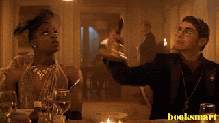 Two people sitting at a dinner table. One on the right rings a bell.