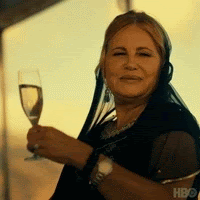 Jennifer Coolidge from White Lotus is standing on a boat, raising a glass of champagne. The caption says, 'Wee Hee!'