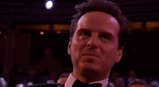 Andrew Scott, in a tuxedo, sitting in the auditorium of an awards ceremony. He's half-smiling, half nodding, and listening to whatever is happening on stage.