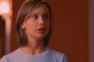 Calista Flockhart as Ally McBeal. She's looking off to the camera, with light brown hair in a straight, shoulder length bob. With camera trickery, in one second her face flushes red.