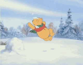 Winnie the pooh is jumping with glee on a snowy mojuntina, picking up snow and throwing it about.