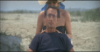 Roy Schneider, as Captain Brody in Jaws, sitting on a beach, looking out to sea. He suddenly looks worried and the camera zooms in on his face.