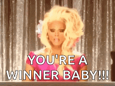Ru Paul, in pink dress and huge blonde wig, is saying, 'You're a winner, baby.'