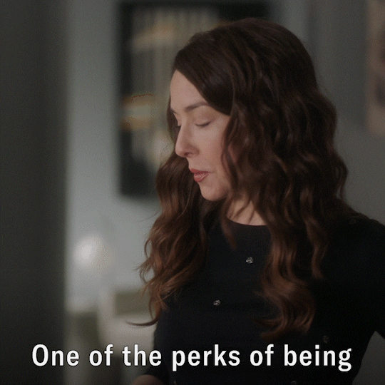 A white woman with long brown hair is saying, 'One of the perks of being the one who makes the schedule.'