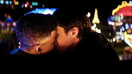 This may contain: two people kissing each other in front of a city at night