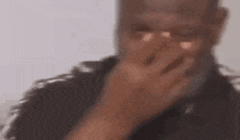 a blurry picture of a man covering his mouth with his hand .