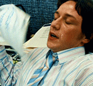 James McAvoy, a white guy with brown hair, is wearing a shirt and tie, in an office, and fanning himself profusely while sweat pours from his face.