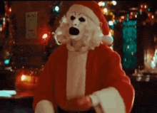 an animated image of art the clown in a santa suit blowing a kiss, with a blood stained gloved then waving