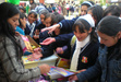 Girls picking up leaflets and pamphlets raising awareness about violence against women